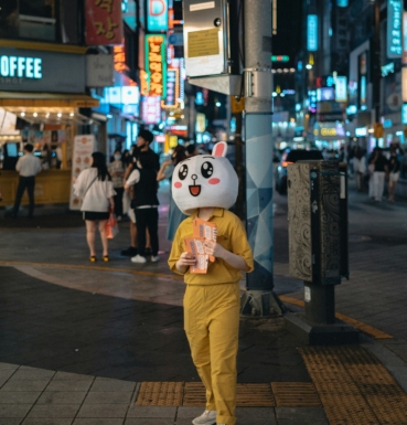 une mascotte de marque distribue des flyers dans la rue